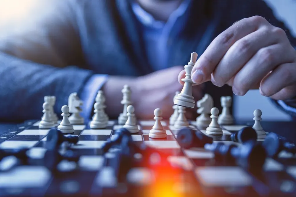 Tangan menata bidak catur di atas papan sebagai metafora strategi